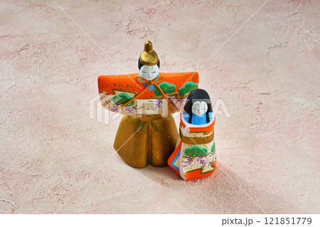 ピンク背景のひな人形（向かって左が男雛、右に女雛）コピースペース有り 121851779