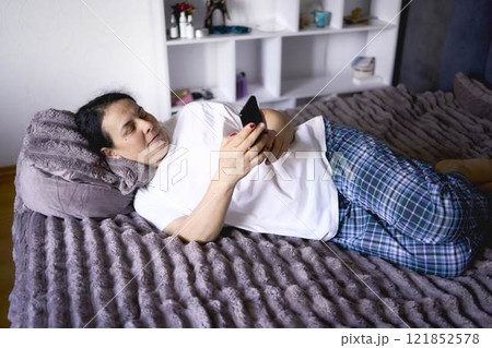 a senior woman chatting on the phone in bed 121852578