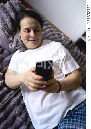 a senior woman chatting on the phone in bed 121852579