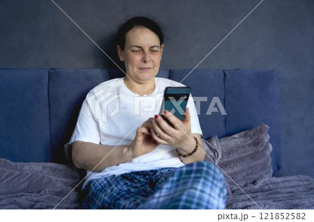 a senior woman chatting on the phone in bed 121852582
