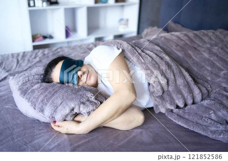 a senior woman in silk eye mask sleeping under heavy blanket a senior woman in silk eye mask sleeping under heavy blanket 121852586