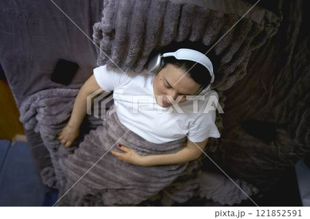 a senior woman wearing sonic hues sleep headphones sleeping under a weighted blanket a senior woman wearing sonic hues sleep headphones sleeping under a weighted blanket 121852591