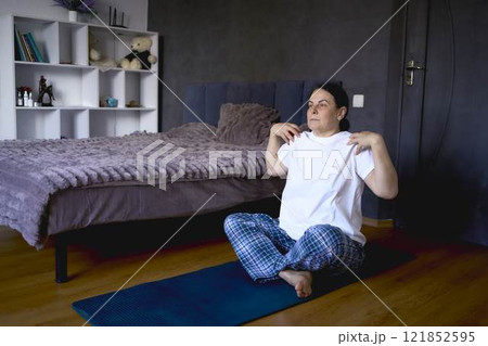 a senior woman performs somatic exercises, yoga at home a senior woman performs somatic exercises, yoga at home 121852595
