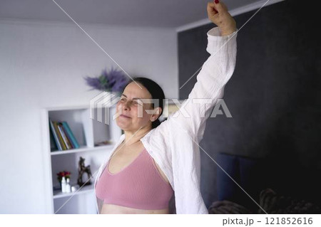 a senior woman in underwear stretching, resting, enjoying life on bed at home 121852616