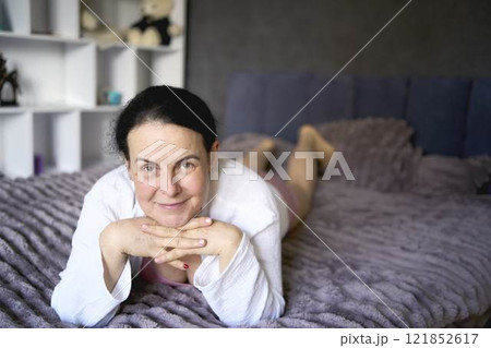 a senior woman in underwear stretching, resting, enjoying life on bed at home 121852617