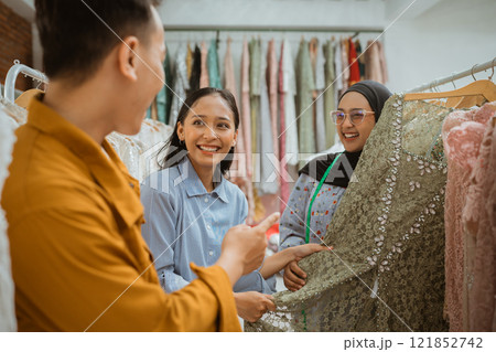 Excited Shoppers Enthusiastically Selecting Fabrics in a Boutique Retail Store 121852742