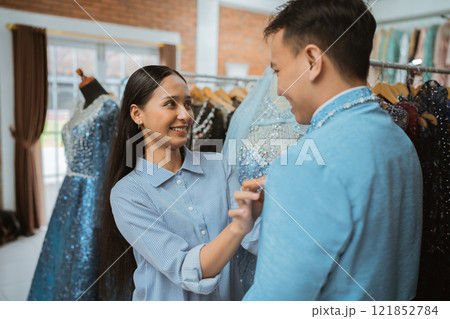 A couple shops for elegant dresses at a boutique, enjoying the experience together A couple shops for elegant dresses at a boutique, enjoying the experience together 121852784