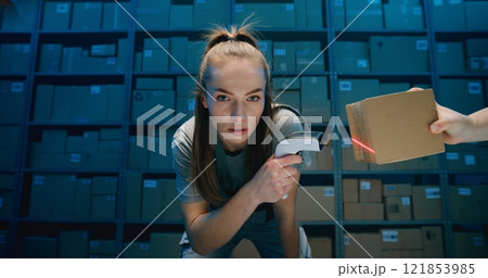 Exhausted Female Warehouse Worker Looking at Camera, Scanning Parcels Using Scanner 121853985