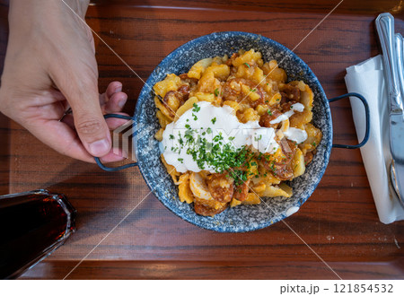 Budapest, Hungary. August 29,2022.. Top view footage of an appetizing dish with a local specialty: potatoes, meat, tomato, chopped parsley. Budapest, Hungary. August 29,2022.. Top view footage of an appetizing dish with a local specialty: potatoes, meat, tomato, chopped parsley. 121854532