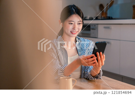 夜にスマホでコンテンツを楽しむ一人暮らしの女性 夜にスマホでコンテンツを楽しむ一人暮らしの女性 121854694