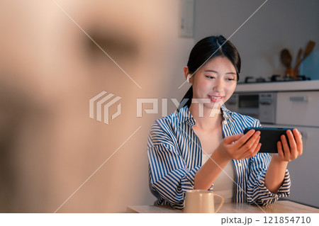 夜にスマホでコンテンツを楽しむ一人暮らしの女性 夜にスマホでコンテンツを楽しむ一人暮らしの女性 121854710