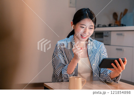 夜に家でスマホでスポーツ観戦をする若い女性 夜に家でスマホでスポーツ観戦をする若い女性 121854898