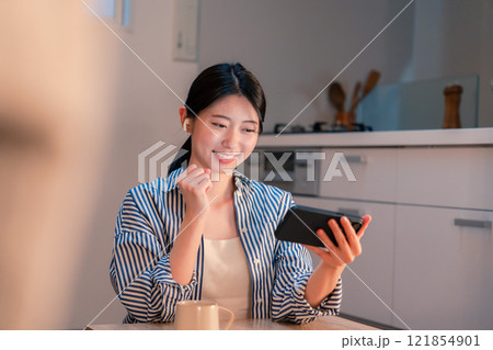夜に家でスマホでスポーツ観戦をする若い女性 夜に家でスマホでスポーツ観戦をする若い女性 121854901