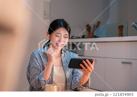 夜に家でスマホでスポーツ観戦をする若い女性 夜に家でスマホでスポーツ観戦をする若い女性 121854903