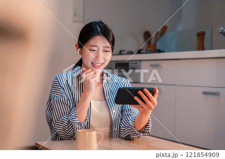 夜に家でスマホでスポーツ観戦をする若い女性 夜に家でスマホでスポーツ観戦をする若い女性 121854909