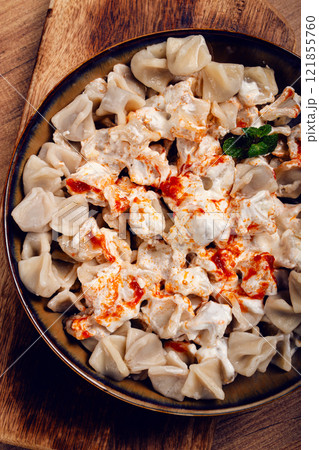 Traditional Turkish dumplings served with yogurt and spicy sauce on a green decorative plate Traditional Turkish dumplings served with yogurt and spicy sauce on a green decorative plate 121855760