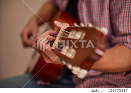 Hand playing an acoustic guitar in a close-up side shot 121855817