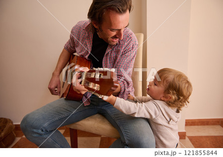 Father bonding with his child while playing the guitar at home 121855844