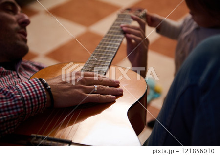 Father and child bonding over playing acoustic guitar at home Father and child bonding over playing acoustic guitar at home 121856010