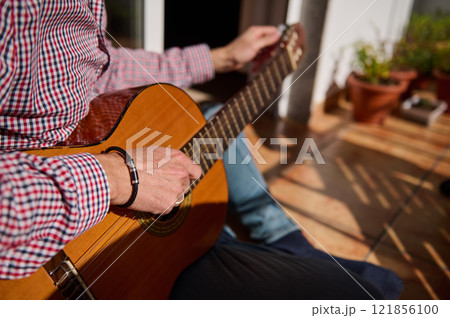 Man Playing Acoustic Guitar Outdoors in a Sunny Relaxing Atmosphere Man Playing Acoustic Guitar Outdoors in a Sunny Relaxing Atmosphere 121856100
