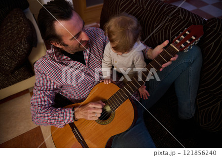 Father and child bonding over acoustic guitar playing at home 121856240