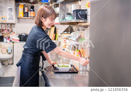 居酒屋の厨房で働くキッチンスタッフの女性 121856356