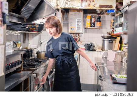 居酒屋の厨房で働くキッチンスタッフの女性 居酒屋の厨房で働くキッチンスタッフの女性 121856362