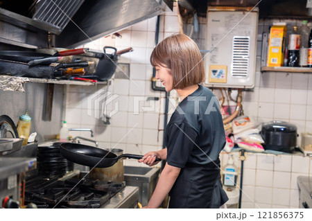 居酒屋の厨房で働くキッチンスタッフの女性 121856375