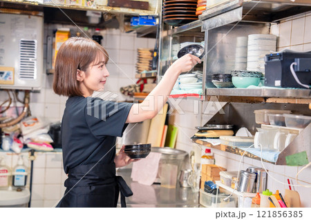 居酒屋の厨房で働くキッチンスタッフの女性 121856385