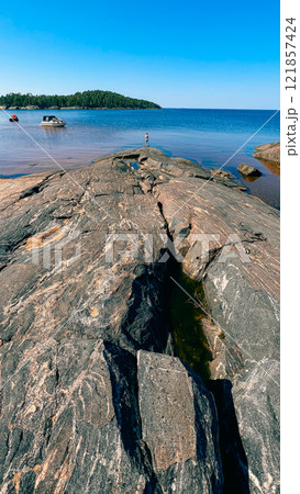 Huge stones and a small figurine of a child on the shore of the White Sea Huge stones and a small figurine of a child on the shore of the White Sea 121857424