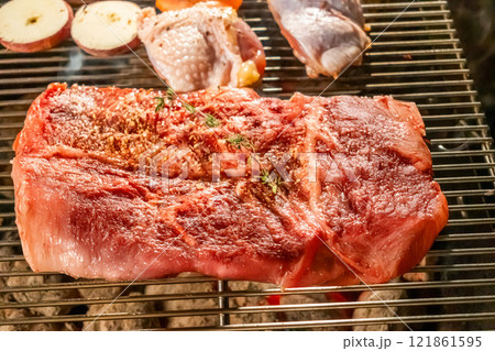 ワイルドに焼くステーキ　Grill a steak over an outdoor 121861595