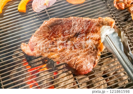 ワイルドに焼くステーキ　Grill a steak over an outdoor 121861598