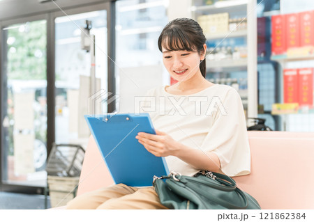 病院・薬局の待合室で問診票を書く妊婦の女性（初診・マタニティクリニック） 121862384
