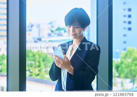 オフィスでスマホを操作するスーツ姿の笑顔のビジネスウーマン撮影協力:LINK FOREST オフィスでスマホを操作するスーツ姿の笑顔のビジネスウーマン撮影協力:LINK FOREST 121863708