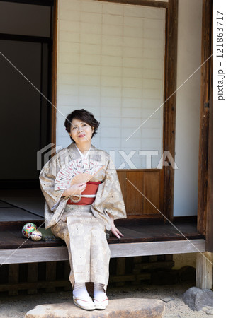 縁側に座って扇子で涼んでいる着物姿の女性 121863717