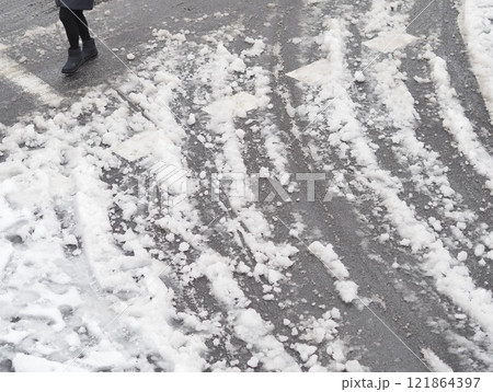 積雪した道路を歩く人と複数のタイヤ跡 積雪した道路を歩く人と複数のタイヤ跡 121864397