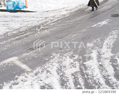 積雪した道路を歩く人と複数のタイヤ跡 積雪した道路を歩く人と複数のタイヤ跡 121864398