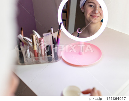 Beautiful young woman facing the mirror and smile.Skin care concept. 121864967