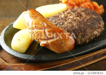 熱々の鉄板で焼き上げたジューシーなハンバーグとソーセージ、ほくほくポテトを添えて 121865632