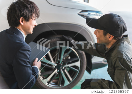 自動車の前で会話する自動車整備士の男性とスーツ姿のフロントマン・営業マン 121866597