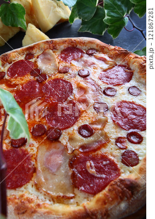 Hearty meat pizza. Pizza with meat ingredients: brisket, hunting sausages, bacon. Two types of sausage and bacon in meat pizza. Close-up. 121867281