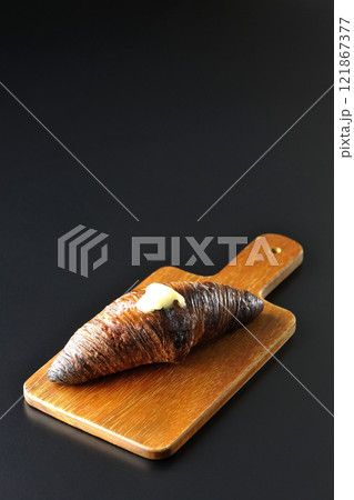 カッティングボードに乗ったちょっと焦げてる黒ワッサンを黒背景で撮影 カッティングボードに乗ったちょっと焦げてる黒ワッサンを黒背景で撮影 121867377
