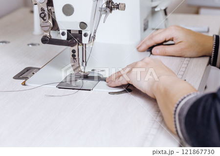 Tanners hands sew black leather strips on a sewing machine indoor, selective focus. 121867730