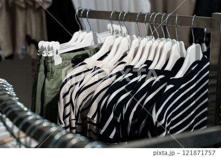 Striped shirts hanging on a rack in a trendy boutique setting 121871757