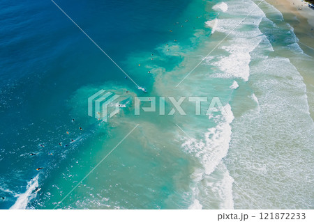 Surfers on surf spot and waves in blue ocean. Aerial view of surfers during surfing Surfers on surf spot and waves in blue ocean. Aerial view of surfers during surfing 121872233