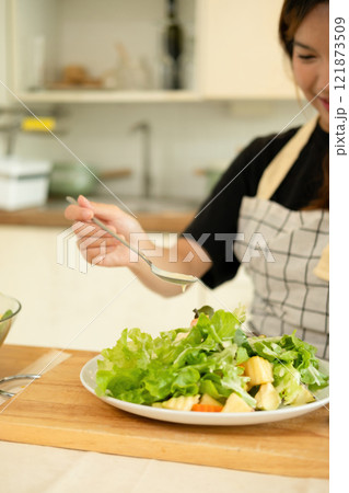 A woman enjoy making salad in the kitchen 121873509
