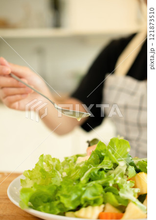 A woman enjoy making salad in the kitchen A woman enjoy making salad in the kitchen 121873510