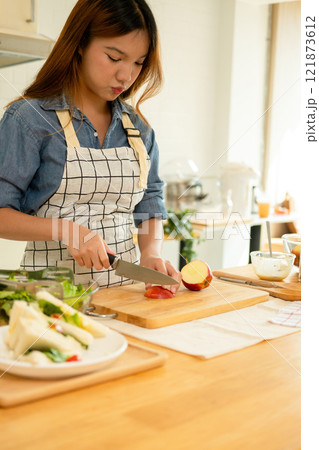 A woman cutting an apple in the kitchen A woman cutting an apple in the kitchen 121873612