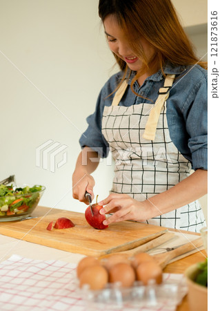 A woman cutting an apple in the kitchen A woman cutting an apple in the kitchen 121873616