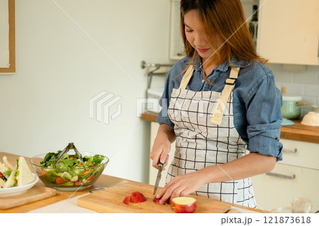 A woman cutting an apple in the kitchen A woman cutting an apple in the kitchen 121873618